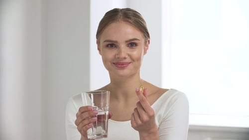 Young Woman Taking Pill with Glass of Water