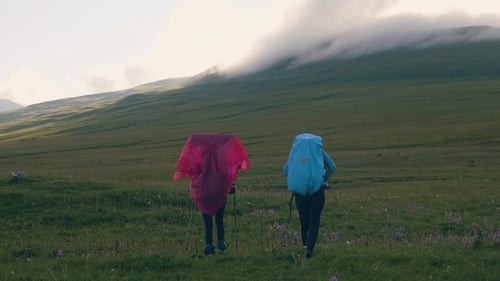 Tourist People Walking on Meadow in Mountain Valley and Cloudy Peaks Background