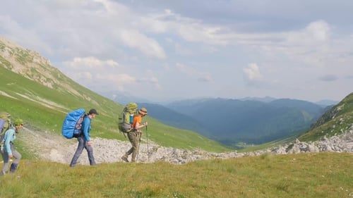 Group of Hiking People Traveling in Mountain on Green Hills and Sky Background