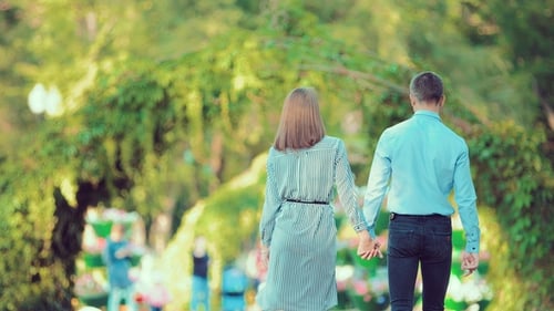 Young Couple Walk Through a City Park Together Heading Away From the Camera