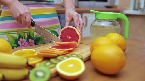 Woman Slicing Grapefruit on Wooden Cutting Board