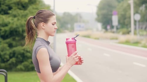 Woman Drinking from Water Bottle After Exercise