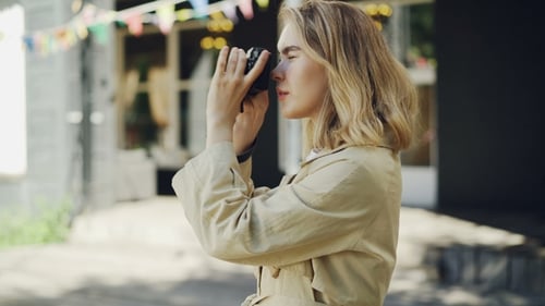 Cheerful Young Girl Is Adjusting Camera Then Taking Photos of Beautiful City Standing Outdoors