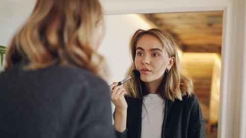 Woman Applies Makeup With Brush In Mirror