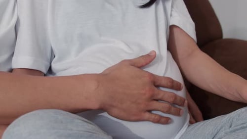 Young Asian Pregnant holding belly feeling happy smiling peaceful while take care baby