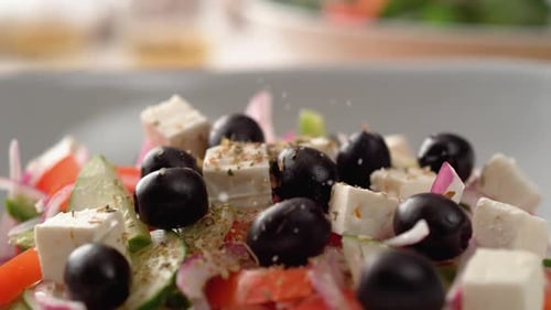La caméra suit le fait de mettre du sel sur une salade grecque Ralenti.