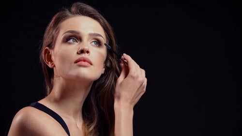 Woman Applies Mascara in Close Up Studio Shot