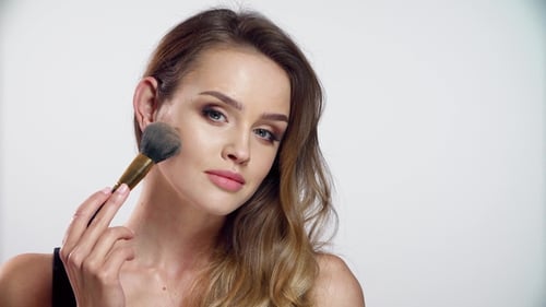 Woman Applies Makeup to Her Face with Brush