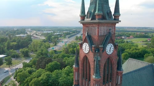 Church in Small City Among Pastures. Drone Footage. Red Church Is Roman Catholic Church