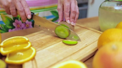 Person Slices Kiwi on Wooden Cutting Board