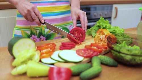 Woman Slicing Fresh Vegetables in Kitchen for Meal