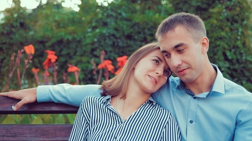 Happy Young Couple in Love Sitting on a Park Bench