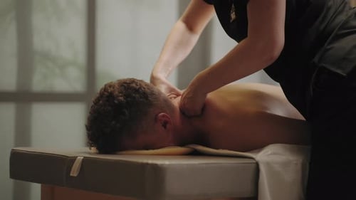 Mann entspannt sich und genießt Massage im Spa-Salon Professionelle Masseuse streichelt den Hals eines Erwachsenen