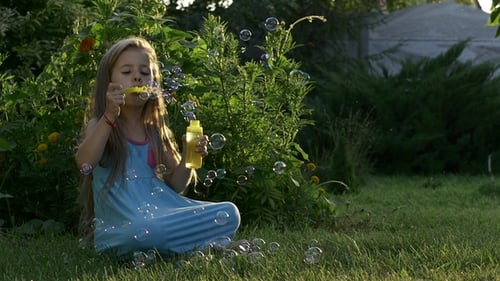 Girl Blowing Soap Bubbles on Green Grass
