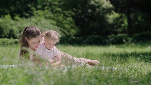 Family Time. Mother And Daughter Resting On Blanket At Park