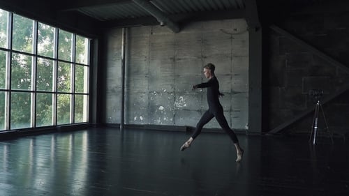 Ballet Dancer Makes a High Jump and Pirouette. Young Man Dancing Against a Dark Background