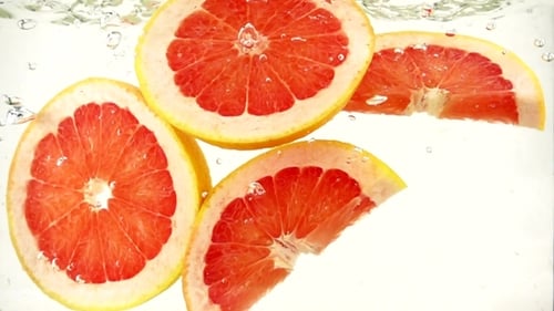 Grapefruit Slices Falling Through Clear Water