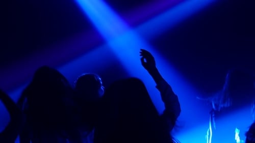 Energetic Crowd Dancing Under Colorful Lights at Night