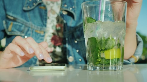Close Up of Hand Using Phone with Drink
