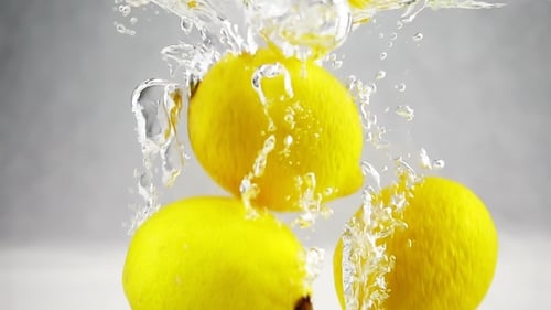 Bright Yellow Lemons Plunging into Refreshing Water