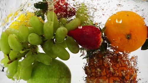 Manzana, kiwi, naranja, pera, limón, uva, piña y bayas caen al agua