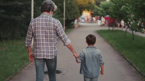 Hippie Grandfather and Boy Walking in the Park Holding Hands