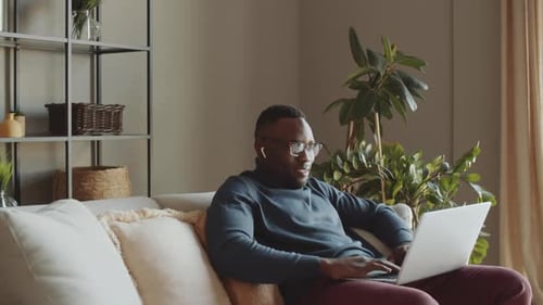 Man Using Laptop on Couch at Home
