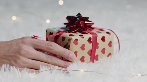 Hand Places Heart Decorated Gift on Soft Fabric