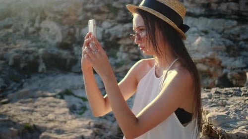 Woman in Hat Posing with Phone by Ocean