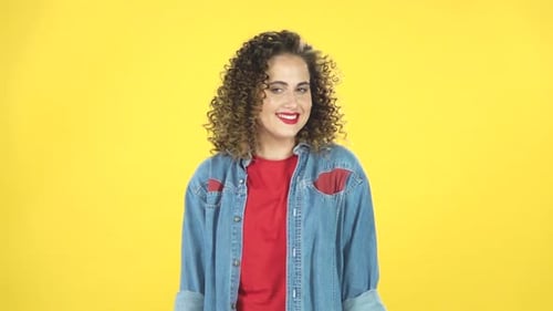 Chica rizada sonríe coquetamente mientras mira a la cámara, construye sus ojos, cámara lenta