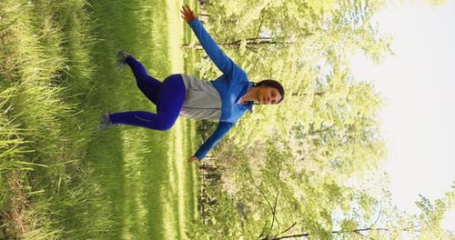 Vertical Video of a 30Yearsold Woman Practices Yoga in a City Park