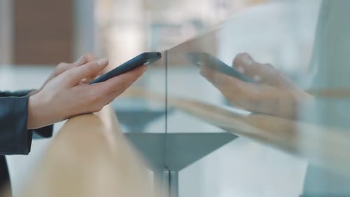 Close-up of Female Hands Holding a Mobile Phone. A Woman Uses a Smartphone with a Touch Screen on a