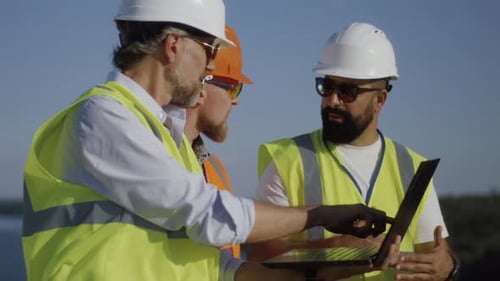 Builders Using Laptop on Construction Site