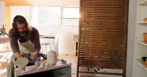 Man Shaping Clay on Pottery Wheel in Bright Studio