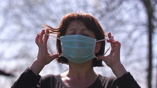 Woman Removes Disposable Face Mask Outside