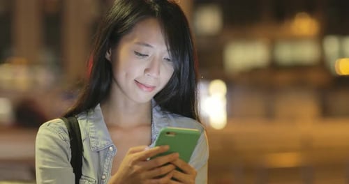Woman using mobile phone at night