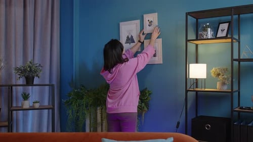 Woman Decorating Home with Wall Art