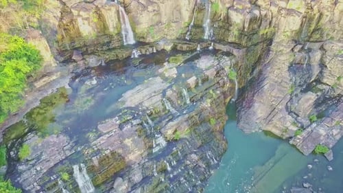 Vista aérea cercana: cascada de rocas a agua azul