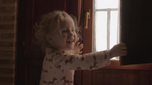 Smiling Child Opens Window in the Morning