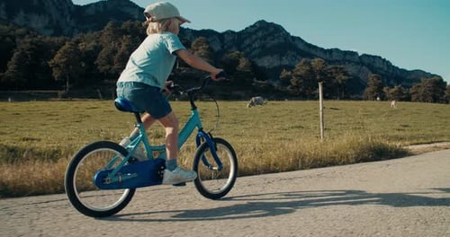 Carefree Child Boy Leads an Active Lifestyle Outdoors Riding Bicycle on Mountain