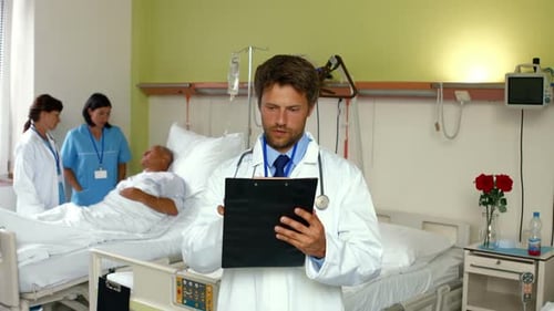 Doctor Reviews Chart with Patient in Hospital Room
