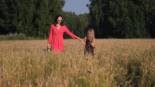 Mother with Daughter and Suitcase Walk in a Field