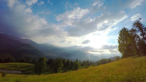 Sun Rays Pass through the Clouds Over the Mountains at Sunset