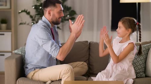 Father and Daughter Playing Hand Game on Sofa