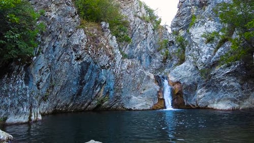 Cascade de Boaza Cascade avec falaises pierreuses envahies par des arbres à droite avec un petit lac en S
