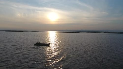 Fischer in einem Boot beim Angeln auf einem Fluss bei Sonnenuntergang.