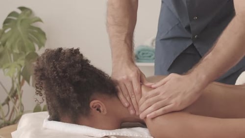 Junge Frau erhält Nacken- und Rückenmassage im Spa-Salon