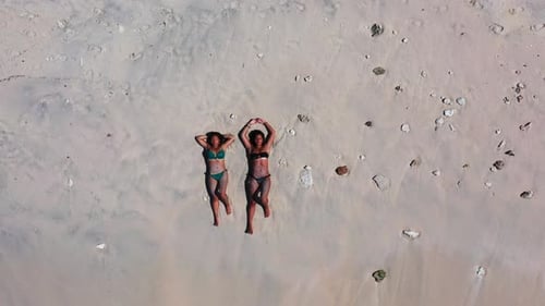 Pretty smiling ladies on vacation spending quality time at the beach on paradise white sand and blue