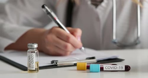 Doctor Writes While Vaccine and Blood Samples Sit