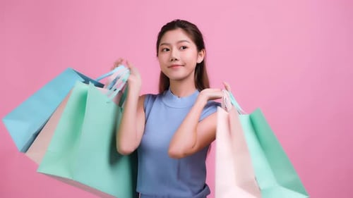 Woman Joyfully Holds Shopping Bags on Pink Background